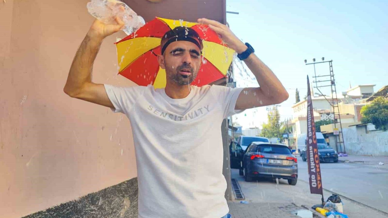 Aşırı sıcaklar nedeniyle kafasına taktığı şemsiye ile geziyor