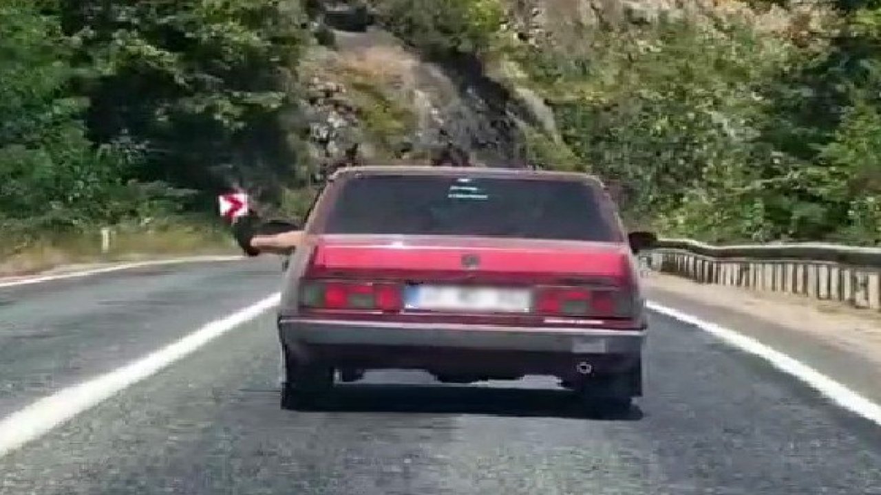 Ayaklarını camdan sarkıtarak trafiği tehlikeye attı