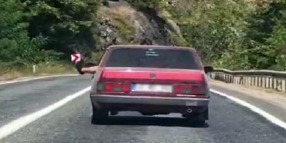 Ayaklarını camdan sarkıtarak trafiği tehlikeye attı