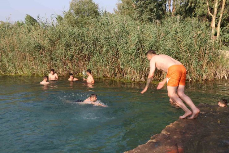 Adana’da gençler bunaltan sıcakta gölette serinledi