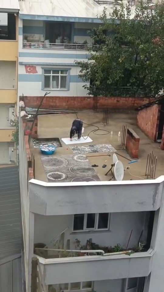 Yağmurlu havada çatıda halı yıkadı, görenler şaştı kaldı