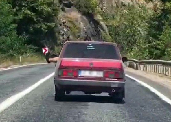 Ayaklarını camdan sarkıtarak trafiği tehlikeye attı